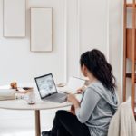 woman in gray sweater using microsoft surface laptop