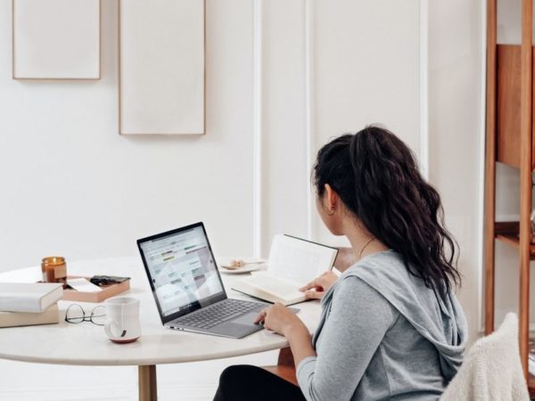 woman in gray sweater using microsoft surface laptop